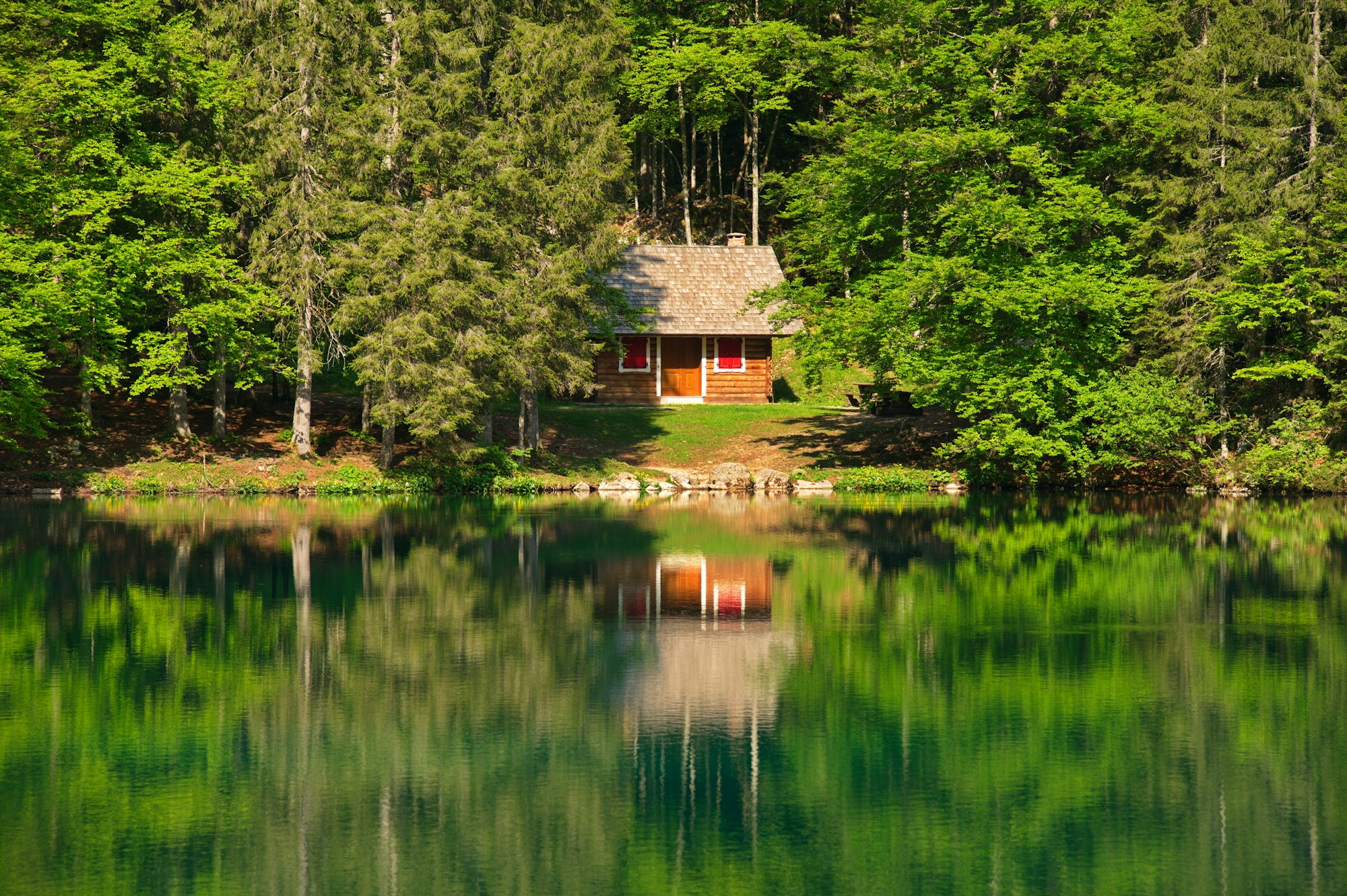 Wooden log cabin at the lake reflected in the water