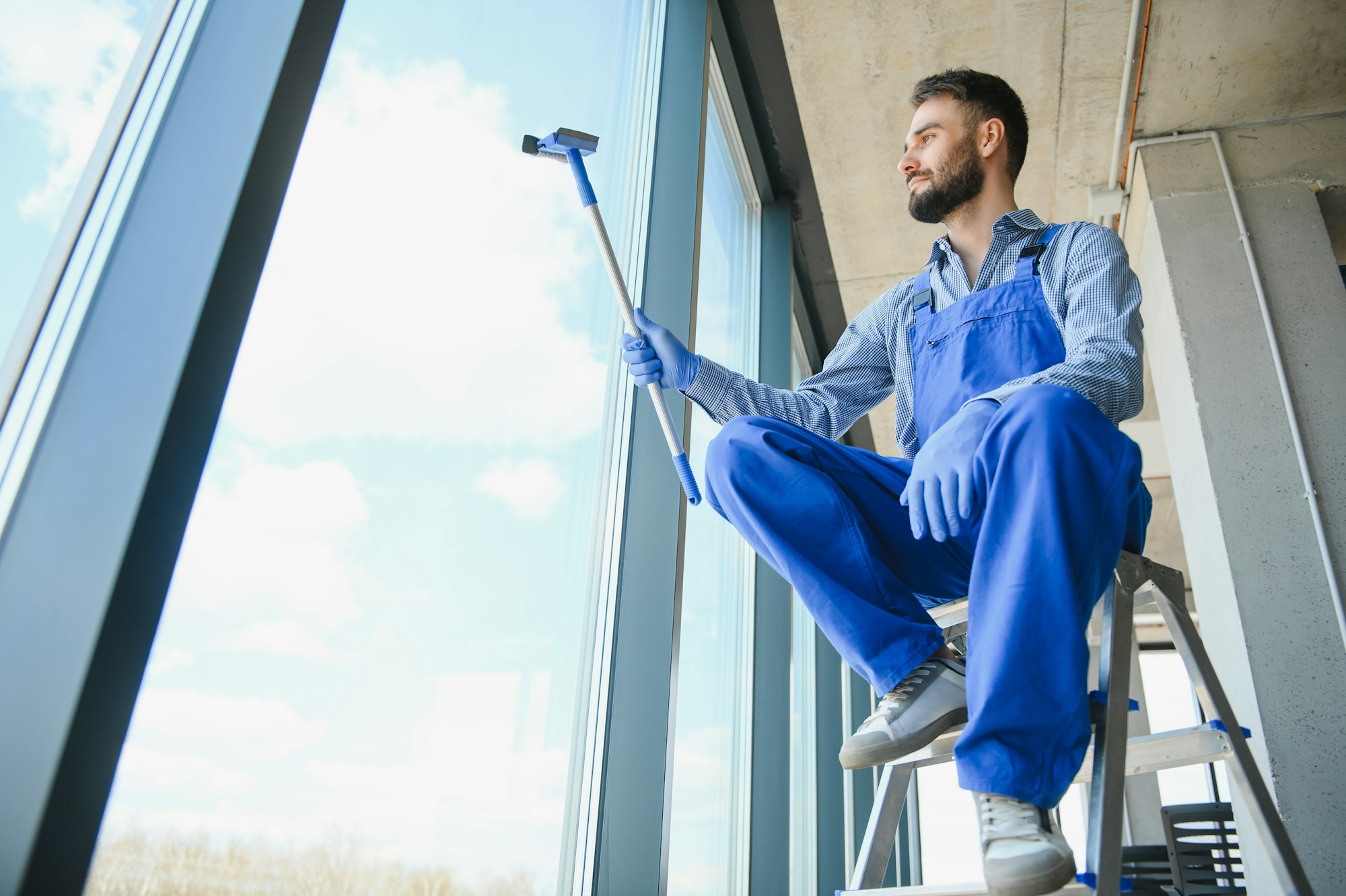 worker cleaning windows service on high rise building